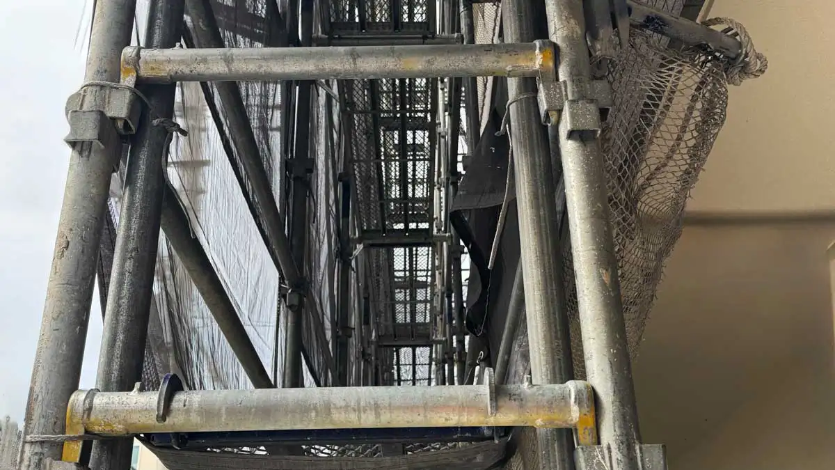 くさび緊結式足場の内部通路の様子。作業床と手すり、メッシュシートの張り具合が確認できる状態。