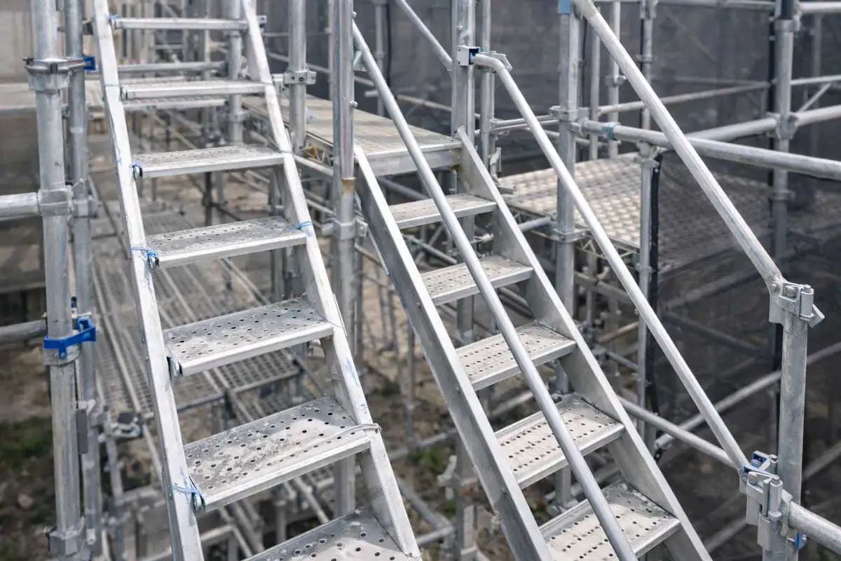 クサビ式足場に設置された昇降設備で、梯子固定と階段ユニットが安全に取り付けられている状態