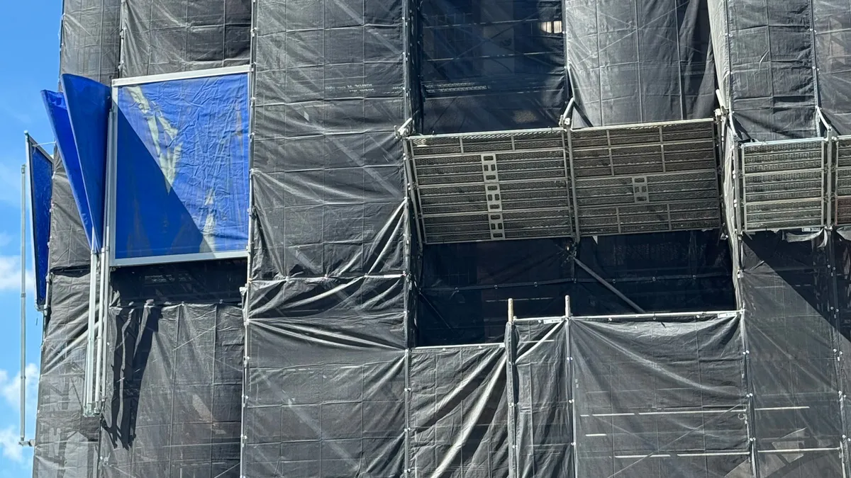 クサビ足場を黒メッシュシートで養生した建築現場の実際の写真｜張り出しステージと防護棚の状態が分かる一次情報