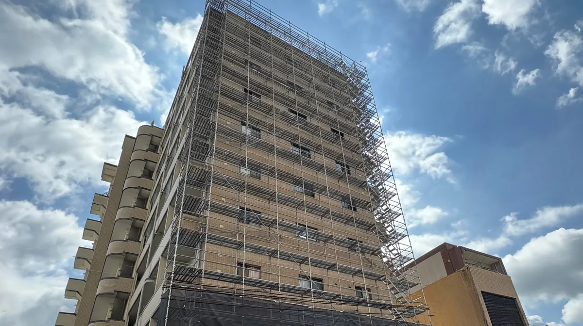 中層マンション外周に組まれたくさび式足場の全景写真。外部足場の価格や積算解説記事の冒頭で使用するための画像。