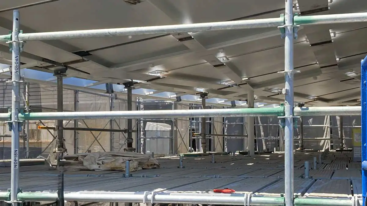 建物内部に組まれたクサビ式足場の施工状況。上部架台の建方に合わせて先行足場が全面に設置され、安全通路と作業床が確保されている様子。