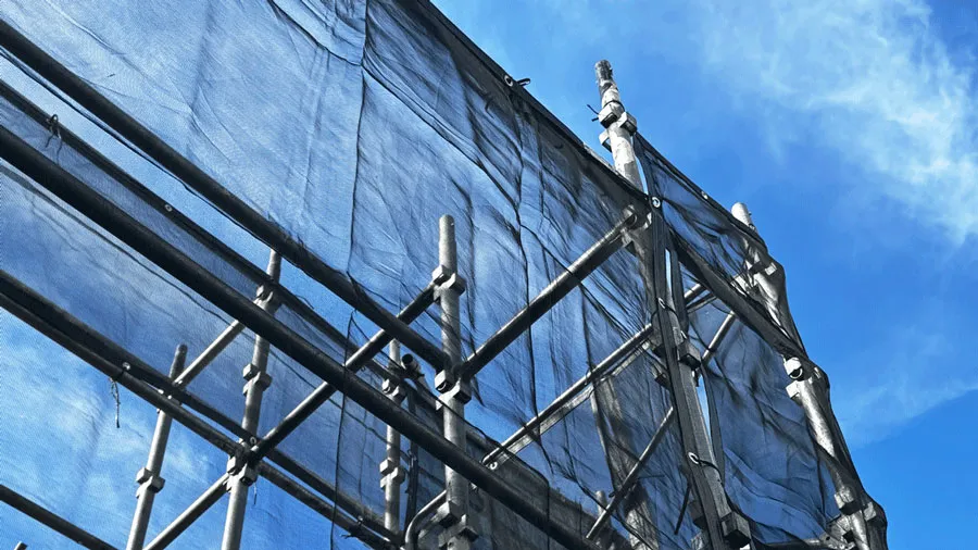 青空の下に組まれたクサビ式足場と養生シート｜安全対策と美観を両立した現場の写真