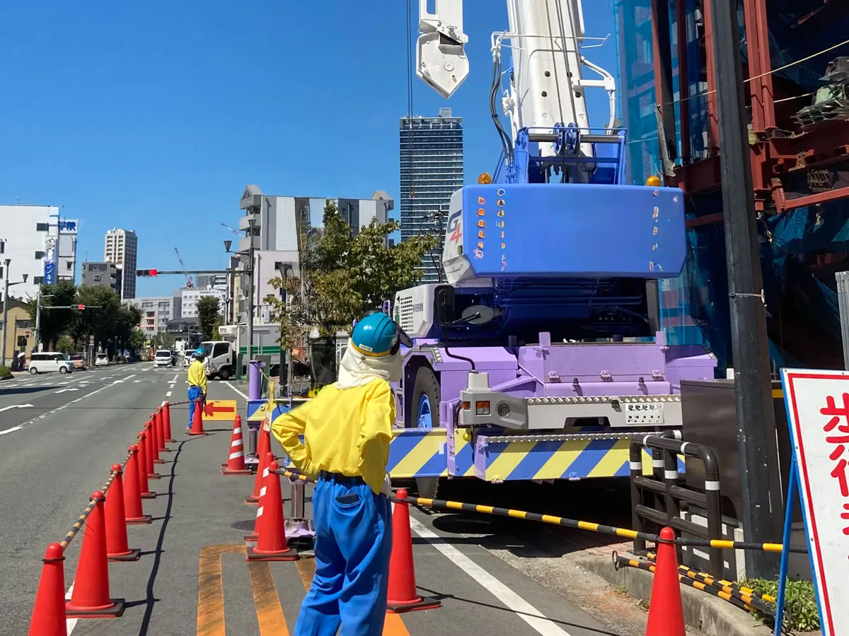 足場回送作業中の現場管理状況|高所作業車と交通誘導員による道路規制の様子